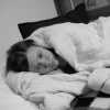 Photo of woman lying in bed, looking sad.