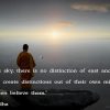 A monk standing on a big rock looking at the sun and the sea.