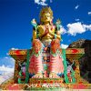 Colorful statue of Maitreya against blue sky in Ladakh.