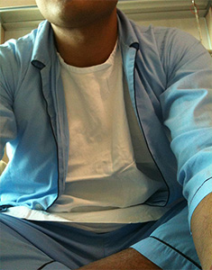 Young man sitting, wearing a blue hospital pajama.