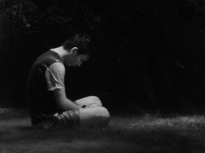 Man sitting with head bowed in contemplation.