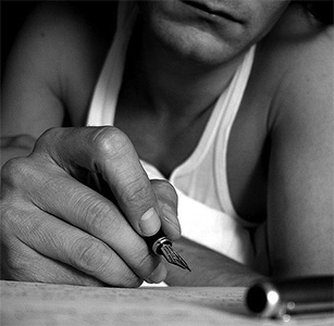 Black and white image of a man writing a letter.