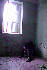 Man slouched in a dark corner.