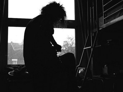 SIlhouette of a man sitting at a window, playing a guitar.