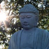 Statue of a Buddha in front of a setting sun.