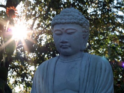Statue eines Buddha vor einer untergehenden Sonne.
