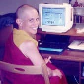 Venerable Chodron sitting at her computer, smiling.