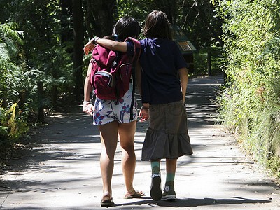 Two girls walking down a path, one with her arm around the other.