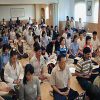 alot of people meditating in a hall.