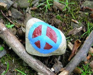 A blue and red peace sign painted on a rock.