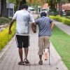 Man helping another young man with a crutch.