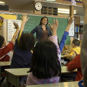 Dzieci w klasie podnoszą ręce, aby zadać pytanie nauczycielowi.