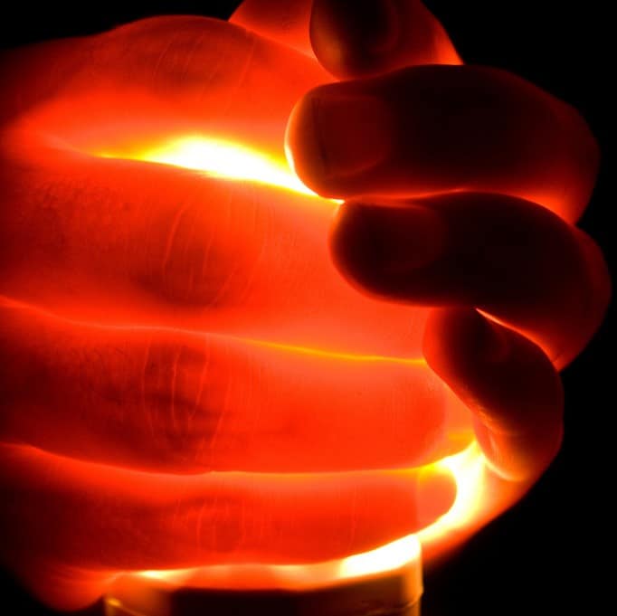 A hand grasping a light bulb.