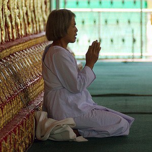 Thai practitioner kneeling with palms together.