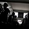 Black and white silhouette of men in a classroom, sitting at desks.
