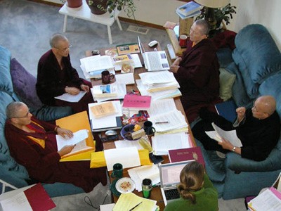 Ven. Chodron, Ven. Jampa Tsedroen, Ven. Heng-Ching Shih und Ven. Lekshe Tsomo sitzt und diskutiert auf einem Tisch voller Papiere.