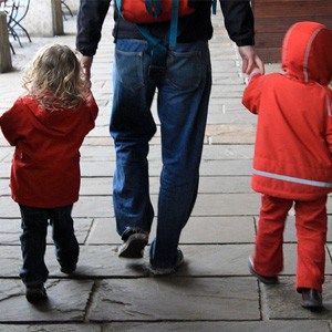 Father walking hand-in-hand with two children.