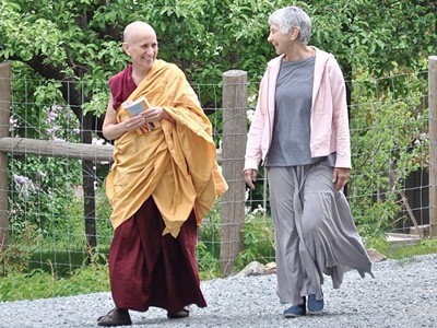 스님 Chodron이 수도원 손님 Tanya와 함께 밖으로 걸어나가고 있습니다.
