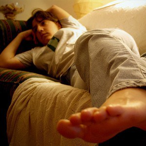 Young woman lying on sofa watching TV.