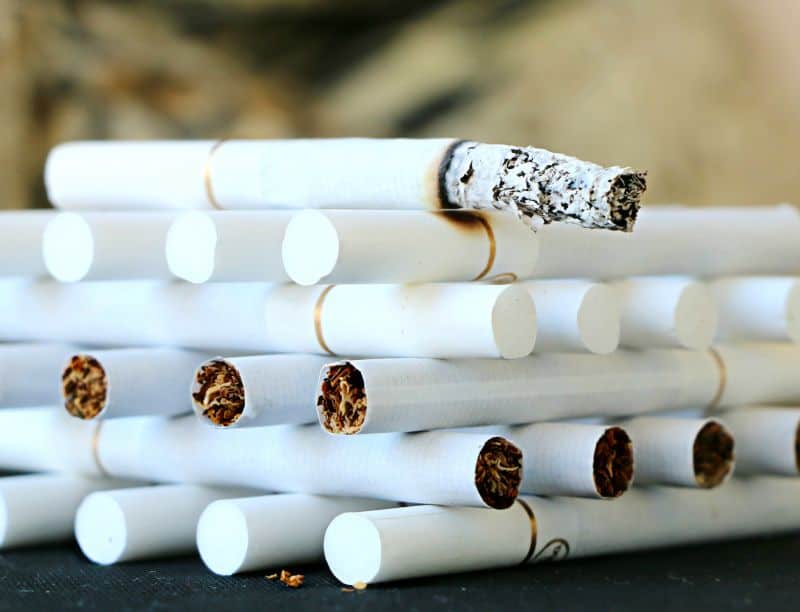 Cigarettes stacked neatly with the top one burning