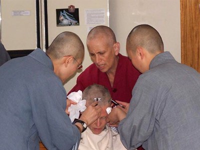Venerable Tarpa getting her head shaved by Venerable and other monastics.