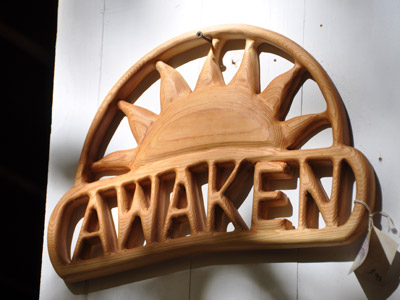 A wood craving of a sun above the word Awaken.
