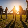 Group of friends standing in circle, holding hands.