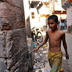 A shirtless young boy walking down a city street.