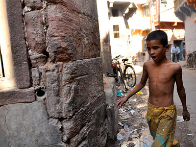 A shirtless young boy walking down a city street.