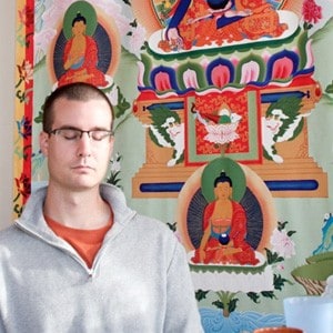 Ken with eyes closed in front of the large Abbey thangka.
