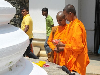 Buddyjskie mniszki Sri Lanki składające ofiary z kwiatów przy stupie.
