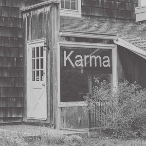Czarno-białe zdjęcie domu z napisem Karma na oknie.