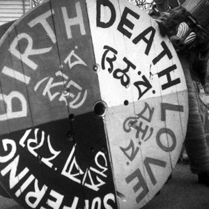 Black and white photo of a big wheel with the words-Birth, Death, Love and Suffering.