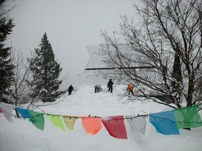 The Abbey covered in snow with prayer flags in the foreground.