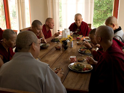 Venerable smiling while eating a meal with other monastics.