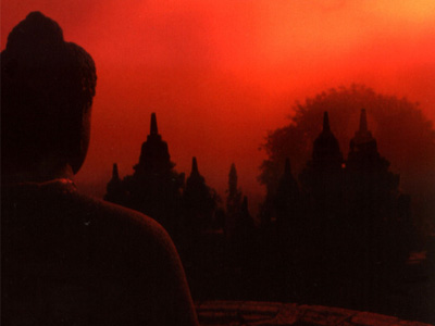 Silhouette of a Buddha statue with bright in front of a fire-red sunset.
