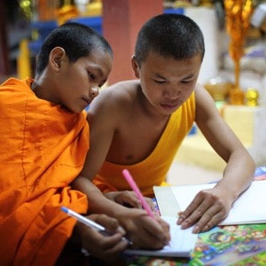 Two novices studying, one novice writing on the paper of the other novice.