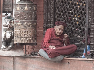 An old woman holding a mala reciting mantra.