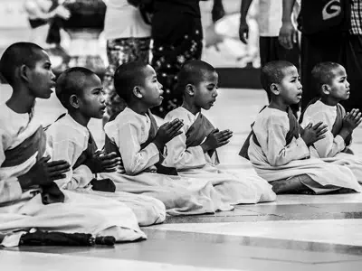 A group of young novice Buddhist nuns in prayer.