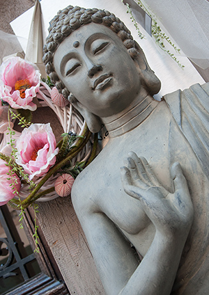 تمثال بوذا كبير مع زهور وردية في الخلفية.