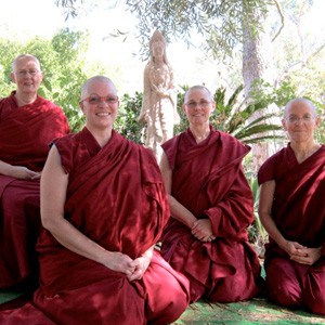 Some of the Abbey monastics sitting in front of a statue of Kuan Yin.