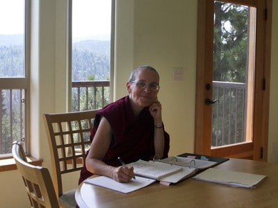 Venerable Thubten Semkye sentada frente a una mesa escribiendo.