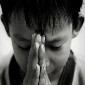 A boy praying in a very sincere expression.