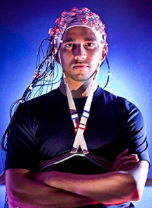 A man wearing a brain cap with alot of wires attached to it.