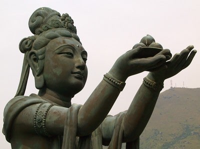 A statue of a woman raising up her hands offering food