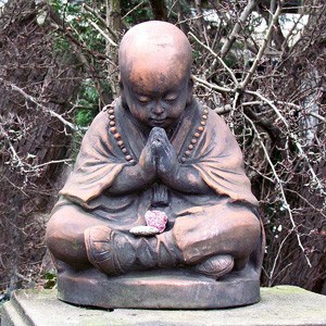 Miedziany mnich siedzący w pozycji modlącej się.