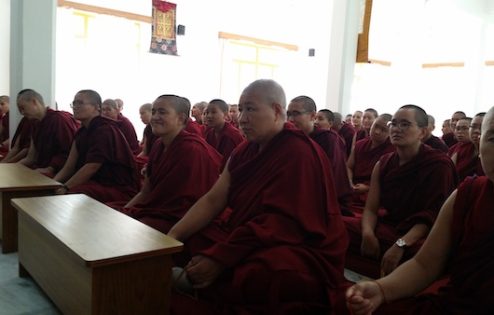 Tibetan nuns seated in a prayer hall.