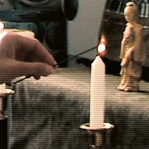 A hand lighting a white candle.