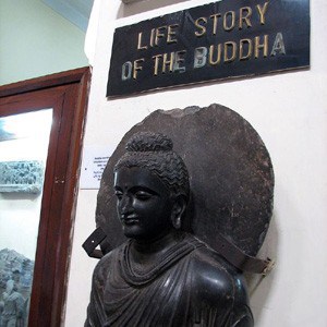 A black statue of a buddha with a sign Life Story of the Buddha
