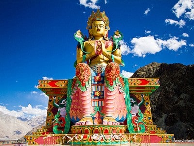 Colorful statue of Maitreya against blue sky in Ladakh.